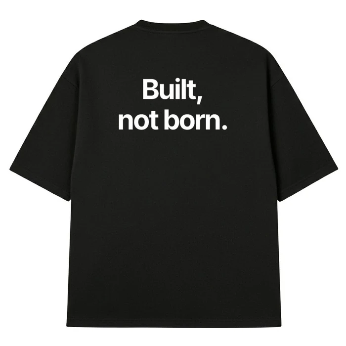 Crna oversize majica, na leđima bela rečenica „Built, not born.“